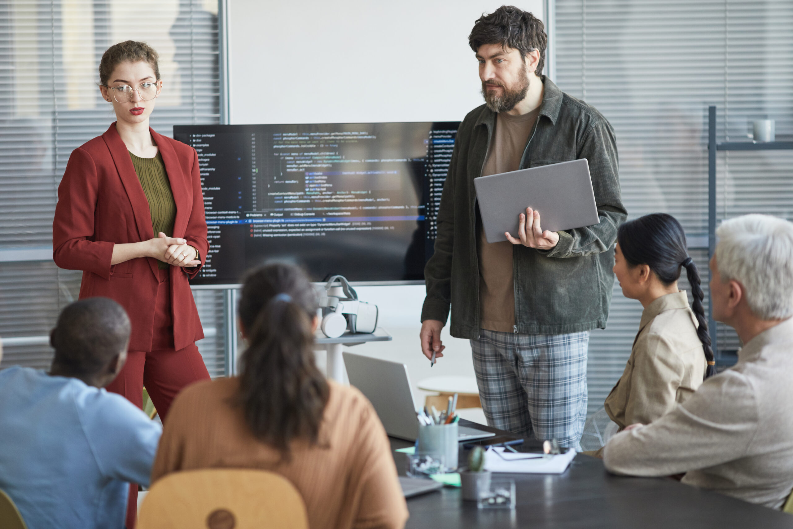 IT Team Discussing Project in Meeting Portrait of mature bearded man giving presentation in office to diverse IT team standing by code on screen